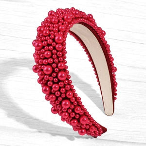 Detail of red padded headband with dense faux pearls on a textured background