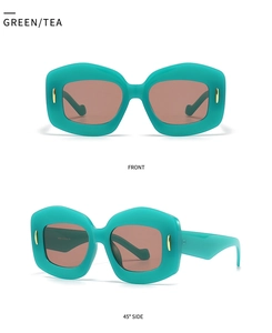 Detail view of irregular polygon sunglasses with green frame and brown tinted lenses