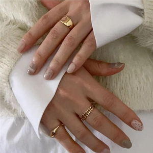 Close-up of golden minimalist rings set including twisted rope and teardrop open designs