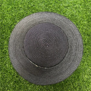 Top-down view of black flat top straw hat with spiral weave on green lawn background