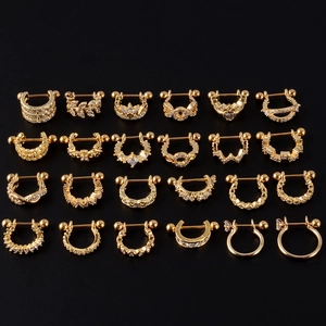 Macro shot of assorted golden piercing studs with leaf, heart and crown zircon designs