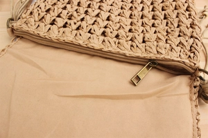 Detail of woven straw bag showing inner fabric lining and smooth metal zipper closure