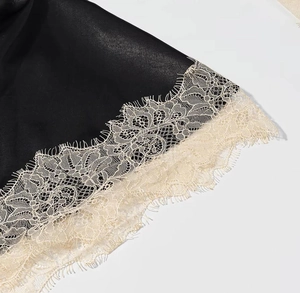 Détail du tissu en satin noir avec des finitions en dentelle de cils blanche raffinée