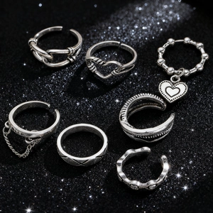 Detail of silver vintage rings set featuring heart and chain motifs on a glittery background
