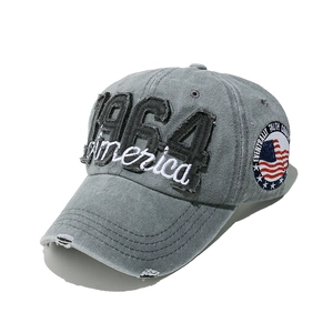 Detailed close-up of 1964 America embroidery and distressed washed gray denim on baseball cap