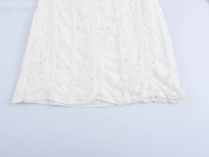 Close-up of white lace mini dress hem showing intricate floral hollow patterns