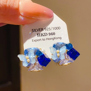 Detail of 925 silver earring featuring blue crystal butterfly and pearl accents