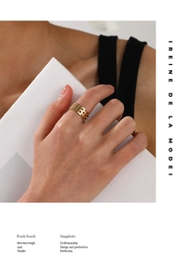 Detail of a wide gold-plated braided chain ring on a model holding a white card