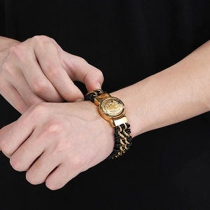 Close-up of men's black braided leather bracelet with golden lion head emblem on wrist