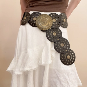 Detail view of retro bohemian belt with round studded discs and embossed brass buckle