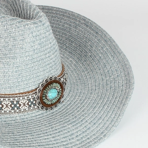 Dettaglio del cappello di paglia grigio-blu con fascia in pelle ricamata e pietra turchese