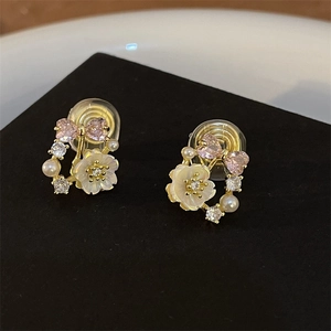 Close-up of vintage flower and pink heart gemstone earrings with pearl details