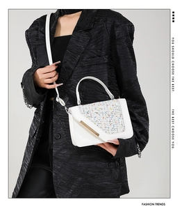Detail of white crossbody bag with colorful tweed flap and gold metal bar buckle