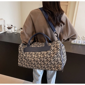 Dettaglio borsa da viaggio con stampa geometrica e manici in pelle blu marino