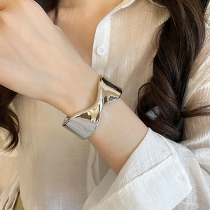 Close-up of a silver minimalist wide twisted cuff bracelet worn on a woman's wrist