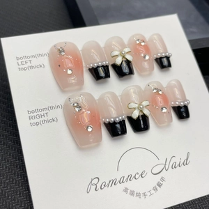 Handmade gradient pink press-on nails with black French tips and 3D bow charms