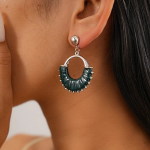 Detailed view of silver hoop earrings with dark green leather texture on a model