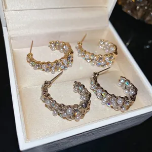 Elegant C-shaped earrings set with sparkling rhinestones and white pearls in gold and silver