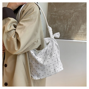 Polka dot bucket bag with white lace bow detail shown on a shoulder in a lifestyle view