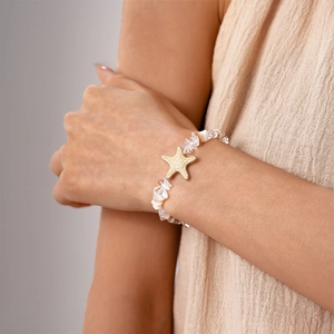 Détail d'un bracelet pendentif étoile de mer avec perles blanches porté au poignet