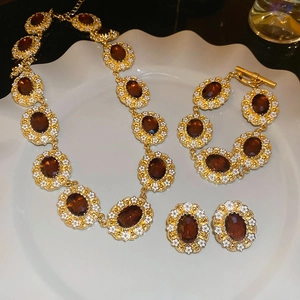 Detailed view of luxury gold jewelry set with amber gemstones and white floral accents