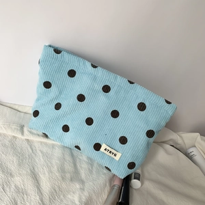 Macro view showing the striped velvet corduroy texture and polka dot pattern of the bag