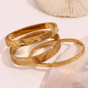 Detailed macro view of three 18K gold-plated stainless steel bangles with water drop design