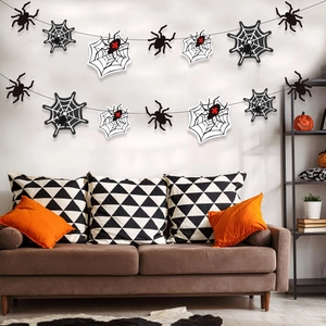 Halloween banner with black and white spiders and webs hanging above a sofa for party decor