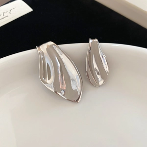 Macro shot of silver metal fishtail earrings with abstract streamlined leaf design