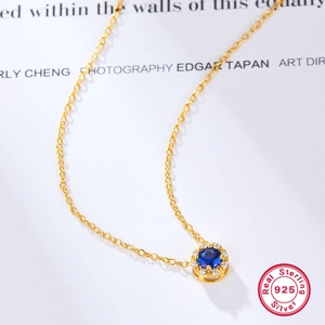 Detail of 925 sterling silver gold necklace with round blue zircon pendant and diamonds