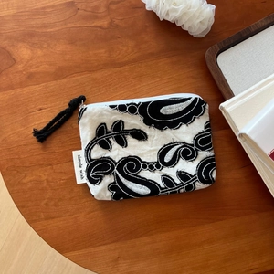 Detail of bohemian linen coin purse with black floral embroidery on wooden table