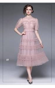Détails de broderie sur le corsage en dentelle rose avec manches bouffantes et tulle