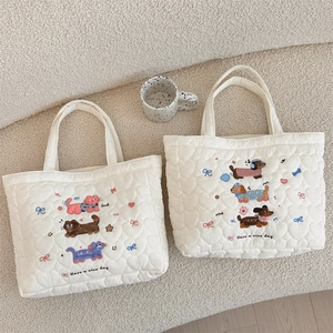Detail of white quilted tote bags with heart patterns and cute animal embroidery