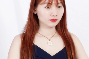 Detailed view of a gold circular pendant necklace with a white mother of pearl inlay