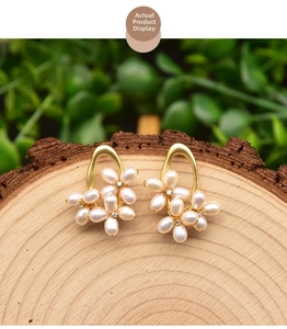 Macro shot of handmade pearl flower earrings with zircons on a rustic wood base