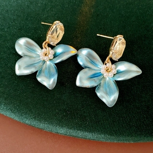Close-up of blue flower earrings with pearls and crystals on dark green velvet background