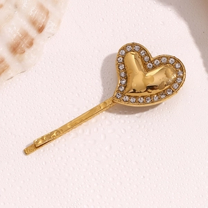 Detailed close-up of a gold-plated heart hair clip with sparkling rhinestones on the edges