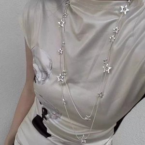 Gros plan d'un collier argenté multicouche orné de pendentifs en forme d'étoiles