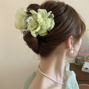 Detail der hellgrünen Organza-Blumen-Haarklammer mit zarten weißen Federn im Haar