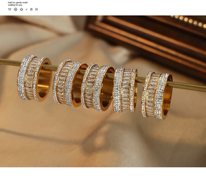 Detailed macro view of five gold-plated rings with zircon pavé on warm silk
