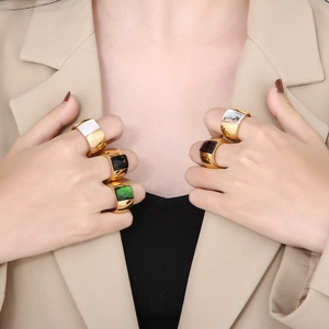 Detailed view of wide gold rings with colorful square gemstones on model's fingers