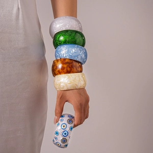 Close-up of acrylic geometric open bangles with colorful marble patterns on model
