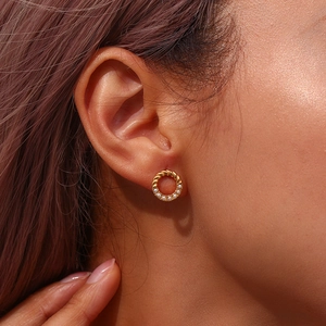 Detailed view of a gold twisted hoop earring featuring elegant inlaid white pearls