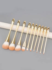 Detail view of 11 professional makeup brushes with gold handles and pink gradient bristles