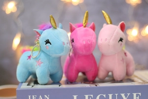 Close-up of three colorful plush unicorn keychains with gold horns and star embroidery