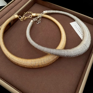 Close-up of gold and silver irregular geometric spiral necklaces on a brown jewelry tray