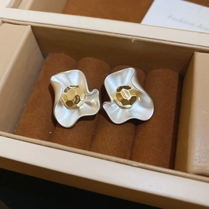 Detail of floral pearl earrings with gold plating on brown velvet jewelry box liner