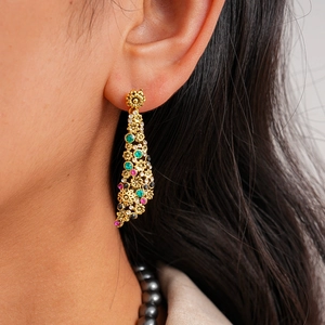 Detail of vintage gold-tone drop earrings with colorful zircon inlay on a model