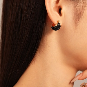 Close-up of vintage geometric basket huggie earrings with black resin beads on a model