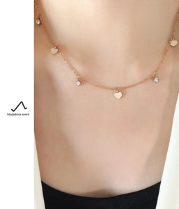 Close-up of rose gold stainless steel necklace with heart pendants and zircons on model